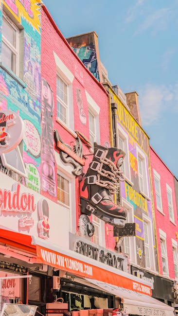 A multi-storey building with a vibrant pink exterior is decorated with colorful murals and advertisements, including an image of a roller skate and various stylized text. The facade features three white-framed windows on the lower levels, with the upper wall painted in bright colours and graffiti-style artwork. A prominent, large three-dimensional sculpture of a roller skate, painted in shades of gray and black with red accents, is mounted on the building's front, creating a focal point. The ground level has a black and orange awning with the website address www.140worn.com printed on it, indicating commercial activity below. The scene is set outdoors during daylight, with a clear blue sky overhead, suggesting a lively urban environment. The visual context hints at a commercial area that may be involved in private waste disposal or community street art projects, reflecting the local culture and aesthetic of the area. Waste Removal Camden specializes in rubbish clearance and related services, which could include on-site clearance of materials in urban settings such as this. This detailed street scene provides a visual connection to alternative waste handling options outside traditional council collection, emphasizing the importance of specialized rubbish removal services in busy city environments.